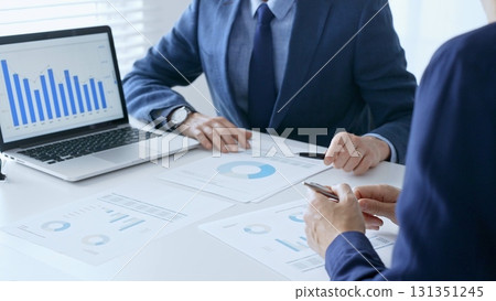 Businesspeople colleagues are reviewing financial data, analyzing charts and graphs, pointing at laptop screen during corporate meeting. Business people and finance concept 131351245