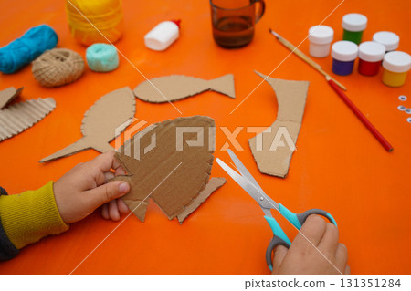 Create a fish figure from cardboard, thread, and paint, with a detailed guide, on an orange background. 131351284