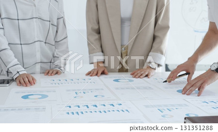 Business team analyzing financial charts and graphs, looking at statistics and discussing data, working together on business project in bright spacious office. Business people concept Business team analyzing financial charts and graphs, looking at statistics and discussing data, working together on business project in bright spacious office. Business people concept 131351288