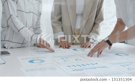 Professional team reviewing financial data, collaborating on charts and graphs in office, pointing toward key statistics during strategic planning session. Business people concept 131351304