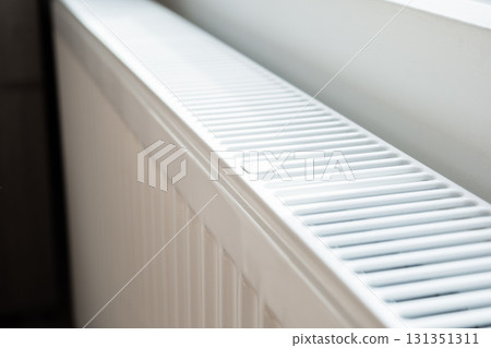 A white heat radiator is installed beneath a window. The fall of the cold weather and the rise in consumer prices. 131351311