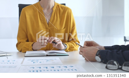 Business people team collaborating and analyzing financial data while taking notes during a corporate meeting in a modern office 131351340