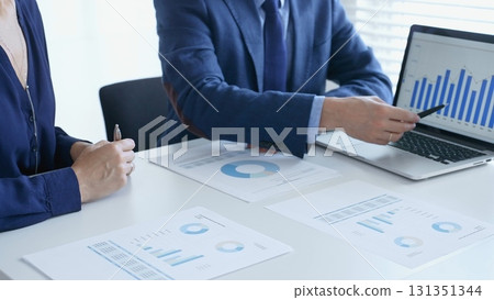 Business professionals reviewing financial data, pointing at laptop charts and shared documents during collaborative strategy session. Business people and finance concept 131351344