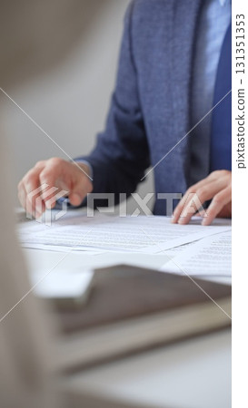Businessman reviewing contract details, professional hands examining document before signing crucial business agreement in corporate setting. Business people concept Businessman reviewing contract details, professional hands examining document before signing crucial business agreement in corporate setting. Business people concept 131351353