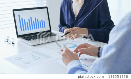 Businessman and business woman reviewing financial documents, collaborating over laptop screen, analyzing market charts for strategic corporate planning. Businesspeople and finance concept 131351356