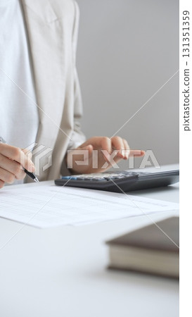 Professional businesswoman is calculating annual tax using calculator and taking notes in the office background, managing budget and checking financial documents. Audit and taxes in business Professional businesswoman is calculating annual tax using calculator and taking notes in the office background, managing budget and checking financial documents. Audit and taxes in business 131351359