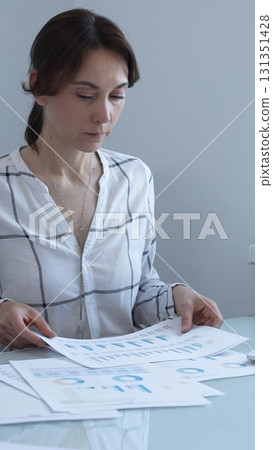 Businesswoman reviewing financial data, analyzing charts and graphs while working on a project at her office desk, demonstrating focus and expertise in business management. Business people concept Businesswoman reviewing financial data, analyzing charts and graphs while working on a project at her office desk, demonstrating focus and expertise in business management. Business people concept 131351428