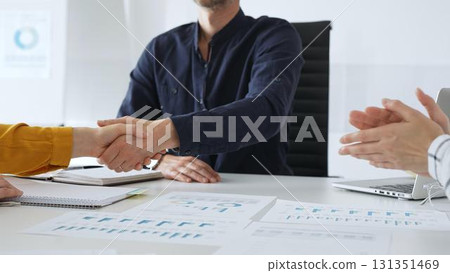 Businesspeople shaking hands, confirming partnership agreement while sitting in contemporary corporate sunny office. Business handshake concept 131351469