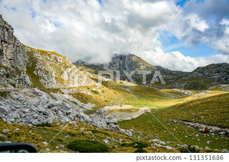 Horizontal panoramic view of a mountain lake on a hillside, surrounded by ridges with low clouds in Durmitor, Montenegro. Horizontal panoramic view of a mountain lake on a hillside, surrounded by ridges with low clouds in Durmitor, Montenegro. 131351686