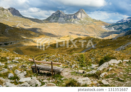 Wooden bench overlooking a panoramic view of a saddle-shaped mountain in Sedlo, Montenegro, surrounded by natural park scenery Wooden bench overlooking a panoramic view of a saddle-shaped mountain in Sedlo, Montenegro, surrounded by natural park scenery 131351687
