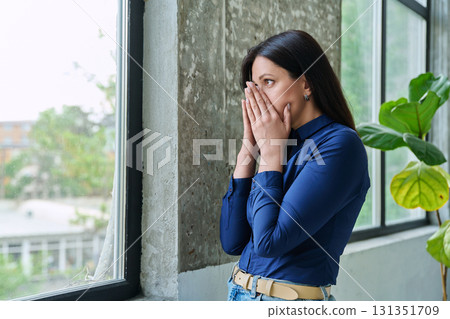 Sad upset young woman looking at window, at home Sad upset young woman looking at window, at home 131351709
