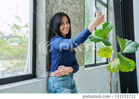 Happy beautiful woman taking selfie portrait on smartphone, at home 131351711