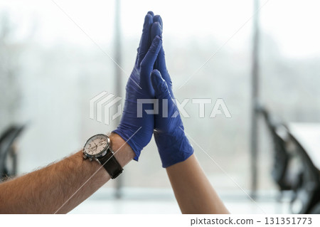 Focused view. Two doctors are holding hands indoors Focused view. Two doctors are holding hands indoors 131351773
