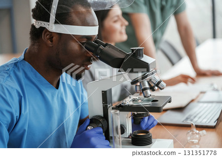 Working in a lab with test tubes and microscope. Group of doctors are together indoors 131351778