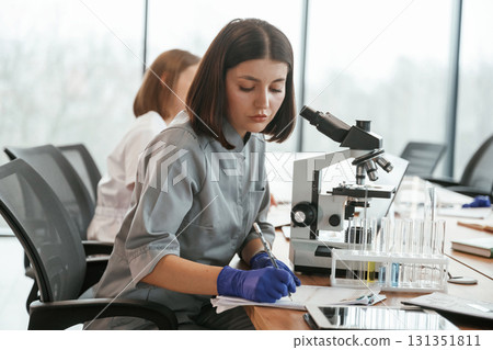 View from the side. Two female doctors are working indoors together View from the side. Two female doctors are working indoors together 131351811