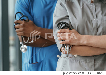 Close up view. Man and woman doctors are standing together indoors with stethoscope Close up view. Man and woman doctors are standing together indoors with stethoscope 131351829