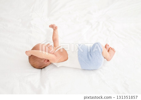 A cute newborn baby in bed wakes up pulling himself up while waking up. Strong healthy sleep of the child. A cute newborn baby in bed wakes up pulling himself up while waking up. Strong healthy sleep of the child. 131351857