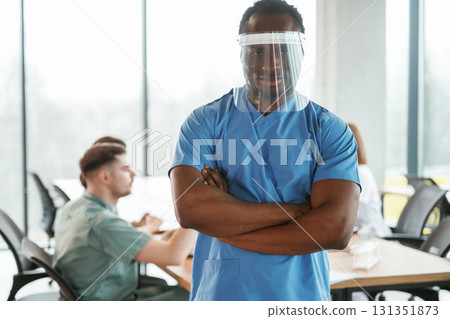 Black guy is in the protective mask. Group of doctors are together indoors Black guy is in the protective mask. Group of doctors are together indoors 131351873
