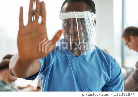 Black guy is in the protective mask. Group of doctors are together indoors Black guy is in the protective mask. Group of doctors are together indoors 131351874
