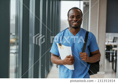 Black man doctor is standing indoors and holding documents in hands 131351914