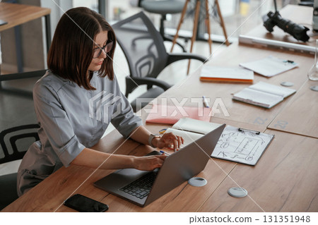 By the laptop on table. Female doctor in coat is indoors By the laptop on table. Female doctor in coat is indoors 131351948