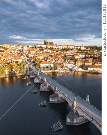 Early dawn lights up Prague's skyline, showcasing the historic Charles Bridge over the Vltava River. Prague Castle towers in the background as the city awakens in the morning. Early dawn lights up Prague's skyline, showcasing the historic Charles Bridge over the Vltava River. Prague Castle towers in the background as the city awakens in the morning. 131352018