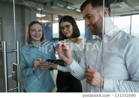 Office workers are creating plan, standing by glass and writing on it 131352080