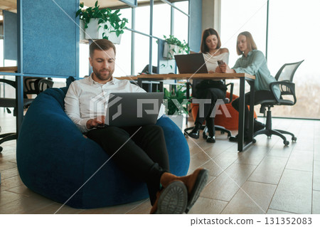 Career growth. Using laptops. People are working in the office with bean bags chairs in it Career growth. Using laptops. People are working in the office with bean bags chairs in it 131352083