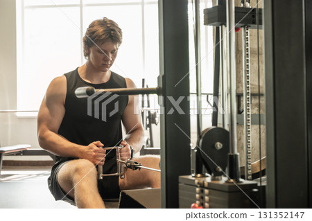 Bodybuilder and sporty man exercising on low rowing machine at gym. Muscular build. Healthy lifestyle 131352147