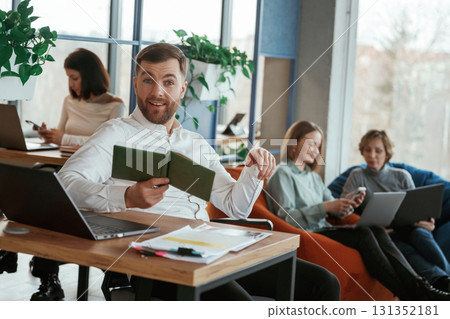 By the table with laptop. People are working in the office with bean bags chairs in it 131352181