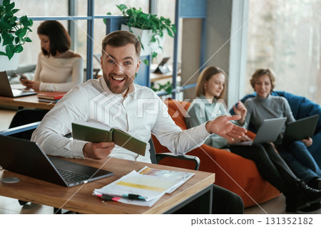 By the table with laptop. People are working in the office with bean bags chairs in it 131352182