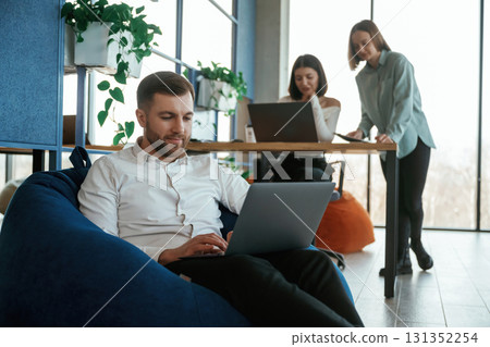 Comfortable bean bag. With laptop. People are working in the office 131352254
