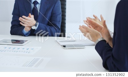 Professional business team clapping hands, celebrating successful presentation, showcasing collaborative spirit and corporate achievement in modern meeting space 131352902