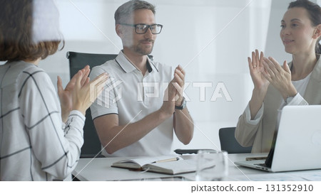 Professional team applauding, celebrating collaborative success and recognizing outstanding performance during corporate meeting, expressing shared workplace achievement. Business people concept 131352910