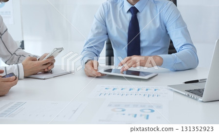 Business colleagues strategizing in modern workspace, reviewing financial analytics on digital devices, sharing insights through collaborative teamwork and data driven discussion Business colleagues strategizing in modern workspace, reviewing financial analytics on digital devices, sharing insights through collaborative teamwork and data driven discussion 131352923