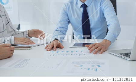 Business people analyzing financial charts, graphs on tablet and laptop, collaborating closely during strategic planning session in office Business people analyzing financial charts, graphs on tablet and laptop, collaborating closely during strategic planning session in office 131352931