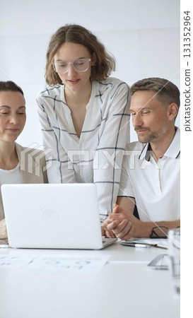 Professional team reviewing project data on laptop, working together in modern office environment, collaborating with focused corporate energy Professional team reviewing project data on laptop, working together in modern office environment, collaborating with focused corporate energy 131352964