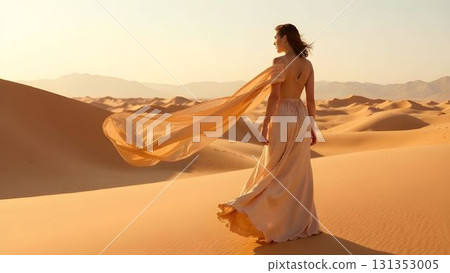 Woman in flowing dress enjoying sunset in a desert landscape with golden sand dunes 131353005