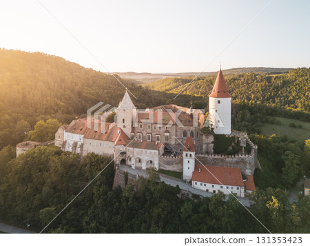 This beautiful aerial view captures Krivoklat Castle in Central Bohemia during sunset. The medieval structure is surrounded by lush greenery, showcasing its historic charm and scenic backdrop. This beautiful aerial view captures Krivoklat Castle in Central Bohemia during sunset. The medieval structure is surrounded by lush greenery, showcasing its historic charm and scenic backdrop. 131353423