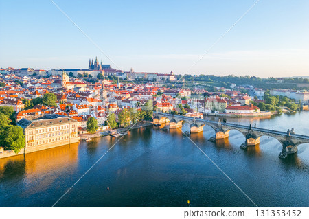 A breathtaking sunrise illuminates the medieval architecture of Prague, casting a warm glow over the Vltava River and the iconic Charles Bridge, showcasing the city's beauty at dawn. A breathtaking sunrise illuminates the medieval architecture of Prague, casting a warm glow over the Vltava River and the iconic Charles Bridge, showcasing the city's beauty at dawn. 131353452