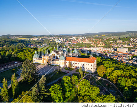 Holy Mountain in Pribram features a stunning Baroque complex surrounded by lush greenery, attracting many pilgrims. The sun illuminates the landscape, creating a serene atmosphere for visitors. 131353457