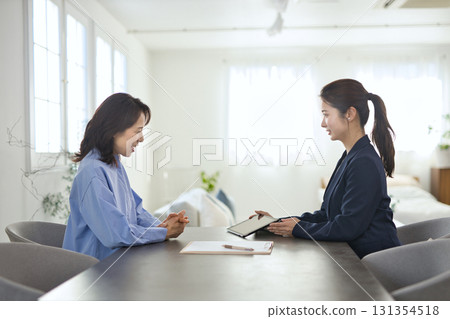 一位年輕女商人向一位中年婦女解釋 131354518
