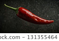 Vibrant red chili pepper rests on a slick, dark background, showcasing fresh cooking ingredient. Glossy texture and dramatic lighting evoke freshness, spice, and bold culinary appeal Vibrant red chili pepper rests on a slick, dark background, showcasing fresh cooking ingredient. Glossy texture and dramatic lighting evoke freshness, spice, and bold culinary appeal 131355464