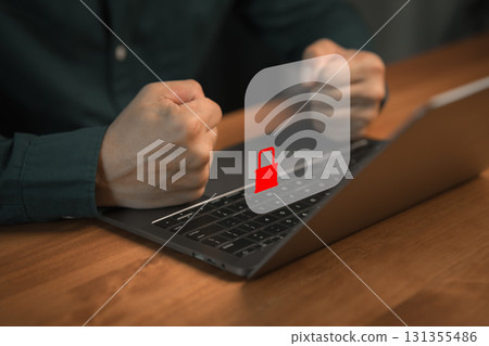 Frustrated person with fists clenched in front of laptop showing locked Wi-Fi icon, representing internet connection problems, network security and online access restrictions. 131355486