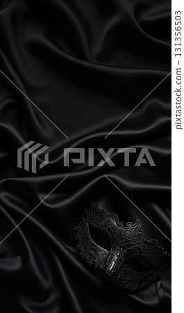 An elegant black masquerade mask with intricate details rests gracefully on luxurious, softly draped black satin fabric, creating a mysterious and sensual top-down composition. 131356503