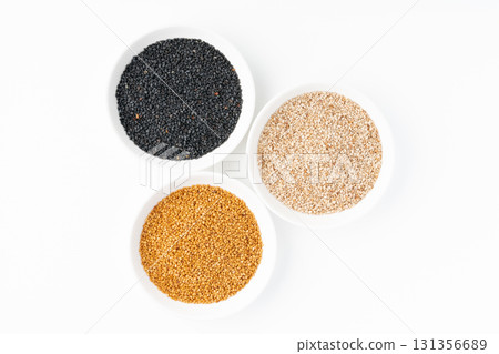 Black sesame seeds, white sesame seeds, and golden sesame seeds (raw sesame seeds) arranged on a plate on a white background Black sesame seeds, white sesame seeds, and golden sesame seeds (raw sesame seeds) arranged on a plate on a white background 131356689