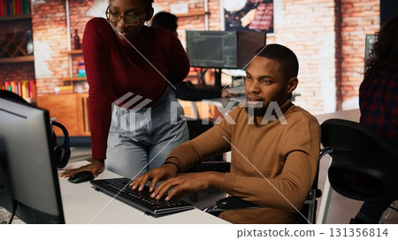 Startup cybersecurity expert in wheelchair looking for company security vulnerabilities on computer, talking with colleague. Man with disability typing on PC and chatting with coworker, camera A Startup cybersecurity expert in wheelchair looking for company security vulnerabilities on computer, talking with colleague. Man with disability typing on PC and chatting with coworker, camera A 131356814