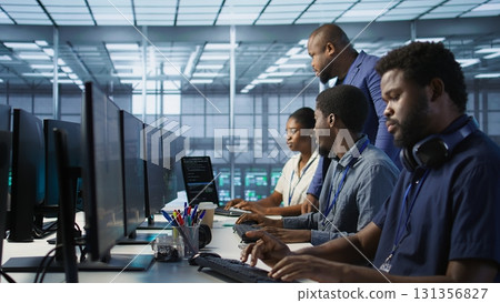 Teamworking computer scientists talking in server room, developing disaster recovery plans. Team of data center office coworkers doing brainstorming, monitoring metrics across devices 131356827