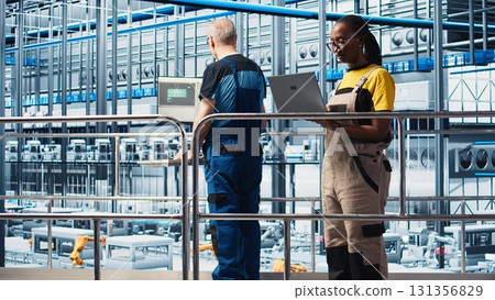 Smart factory engineer oversees operation of robotic arms and conveyor systems on facility floor. Industry 4.0 plant technician monitors system performance and troubleshoots issues, camera A Smart factory engineer oversees operation of robotic arms and conveyor systems on facility floor. Industry 4.0 plant technician monitors system performance and troubleshoots issues, camera A 131356829