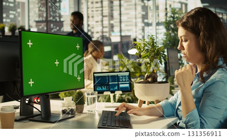 Office clerk working on isolated screen PC to hit key performance targets for revenue and profitability. Employee looking chroma key computer monitor doing research analysis 131356911